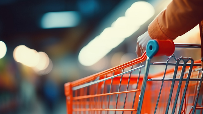 In this close-up image, a woman's hand is pushing a shopping car Das Ifo Institut registriert eine verschlechterte Geschäftslage im Einzelhandel. Bild: Adobe Stock
